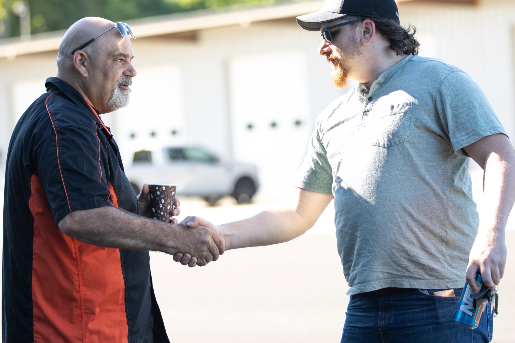 Two transmission industry colleagues shaking hands outside a shop
